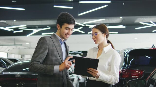 Sales representative discussing vehicle options with a customer in a car dealership during daytime