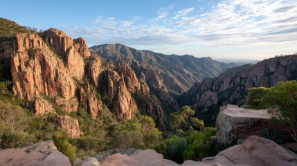 Towering rock formations emerge from lush green valleys as golden sunlight casts dramatic shadows at dawn, showcasing the beauty of elevated terrain