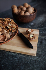 walnuts in a plate on a wooden board.shelled nuts and a knife