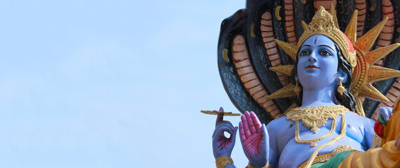 Mahavishnu against the sky with space for text. Blessing Vishnu with chakra in hand.