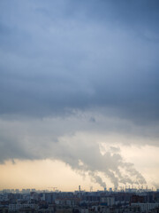 Dramatic cityscape with factory chimneys releasing thick smoke into cloudy sky, symbol of climate crisis, global warming, air pollution and environmental destruction  
