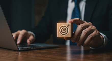 Aim High: Business Strategy & Goal Setting Success - Man with Target Cube, Laptop, & Suit on Wooden Desk. Achieve Your Objectives Today!