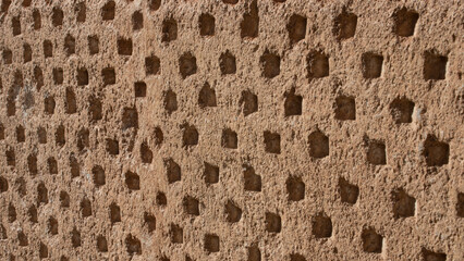 Texture of an old stone wall with small repetitive orifices