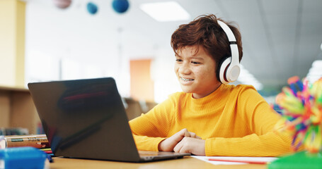 Child, library and headphones with laptop for video call, e learning or online english class for knowledge. Virtual school, development and happy student on technology for growth on teaching platform