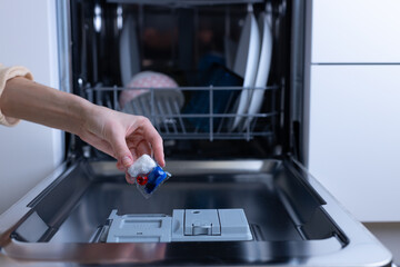 User placing a dishwashing pod in an open dishwasher, emphasizing the importance of proper cleaning...