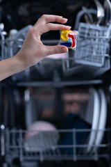 Holding a Colorful Dishwasher Pod in Front of a Full Dishwasher Ready for a Cycle, Illustrating Modern Kitchen Cleaning Solutions and Convenience in Household Chores