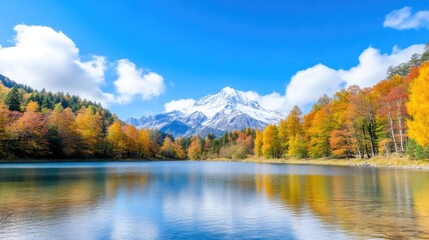 Autumnal mountain lake scenery.  Tranquil autumnal lake reflecting majestic snowy peak, vibrant fall foliage