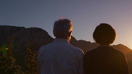 A senior couple standing side by side in a peaceful mountain landscape, seen from behind. A symbol of lasting love, active aging, and appreciation of nature's beauty.