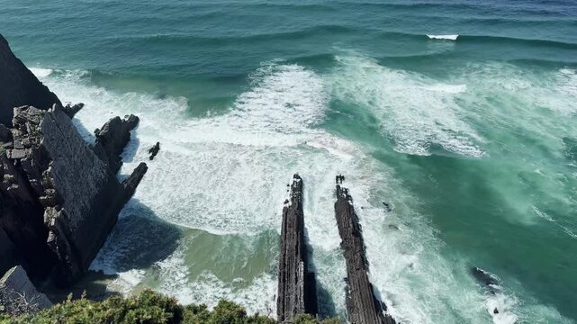 Rocky Cliffs and Crashing Waves in Portugal
Dramatic coastal scene of waves hitting black rocky cliffs from a high viewpoint on the Portuguese shoreline.