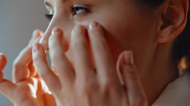Closeup woman caring facial skin making self massage with hands in bathroom. 
