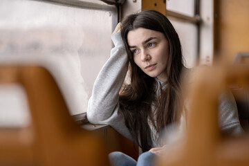 Thoughtful Young Caucasian Woman Looking Through Train Window Wearing Casual Sweatshirt. Lisbon,...