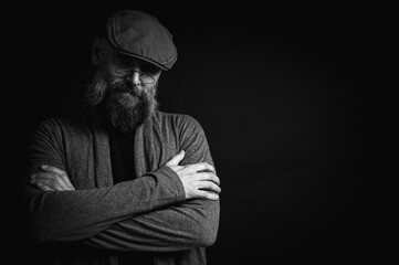 Black and white, portrait of an emotional bearded man in a gray hat, gray sweater and glasses...