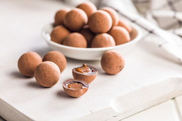 Chocolate truffles with cocoa powder and caramel filling on kitchen table.