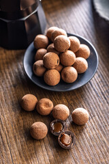 Chocolate truffles with cocoa powder and caramel filling on wooden table.