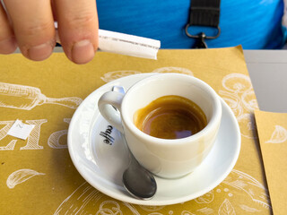 Male adding sugar to espresso in cafe setting
