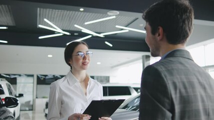 Sales representative discusses vehicle options with a customer in a modern car dealership during afternoon hours