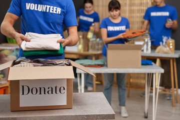 Group of volunteers packing donation goods at tables indoors, selective focus