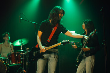 Guitarist and bassist performing on stage with green lighting
