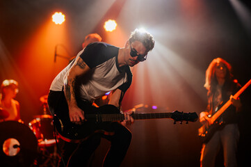 Guitarist performing energetically on stage with bandmates