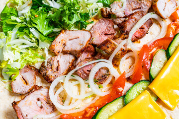 Savory meat wrap preparation with fresh vegetables and cheese