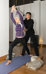 Yoga teacher helping older woman exercise