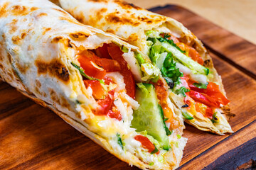 Delicious wrap filled with fresh vegetables and chicken served on wood