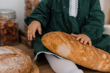 baby girl in the kitchen holds bread in her hands