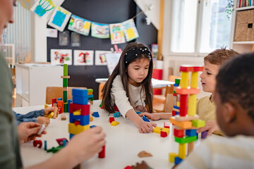Multicultural group of young children building with colorful blocks in a creative preschool classroom, enhancing teamwork, focus, and motor skills during a fun group activity.