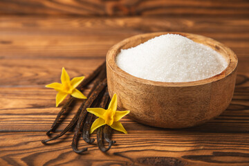 Aromatic vanilla sugar. Vanilla pods. Vanilla sticks, brown and white sugar in a bowl on a textured background. Vanilla flowers, spices and herbs for desserts and baking. Space for text. Copy space