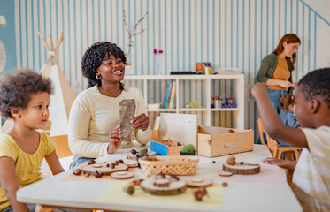 Diverse group of preschool children engage in a nature-based learning activity with two teachers, using wood and natural objects to explore creativity and tactile skills in the classroom.