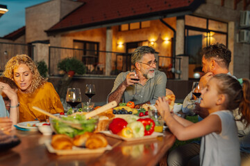 Family enjoying dinner together on a summer evening in their backyard