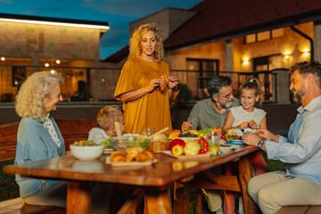 Family enjoying evening meal together in backyard of their house