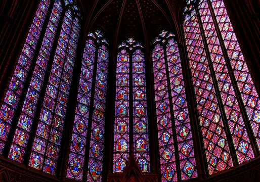 Vibrant stained glass windows illuminate the Gothic interior against a black backdrop.