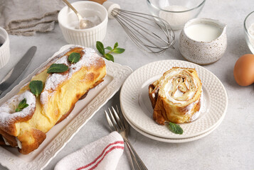 A piece of Finnish pancake in roll with cream on white plate