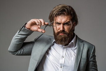 Hairstylist at barber shop isolated on grey. Barber using scissors. Hairstylist serving at barber shop. Barbershop. Barbershop, scissors, moustache, beard. Man holding scissors