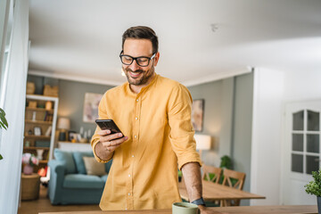 One adult man with eyeglasses stand at home use mobile phone
