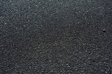 Close-up image of black volcanic sand. The fine, gritty texture and dark tone make it ideal as a natural background or texture for design and creative projects.