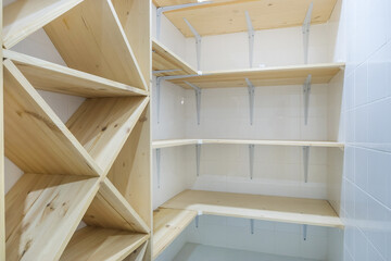 A storage system with shelves made of light wood in a room decorated with white tiles.