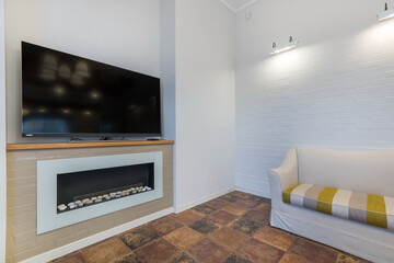 The interior of the living room has a modern design in white tones with a built-in electric fireplace. Floor tiles in the Mediterranean style.