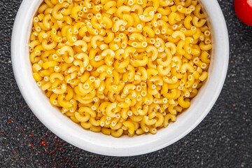 Macaroni pasta raw coquillette appetizer dish organic product fresh tasty gourmet food background on the table rustic food top view copy space