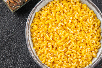 Macaroni pasta raw coquillette appetizer dish organic product fresh tasty gourmet food background on the table rustic food top view copy space