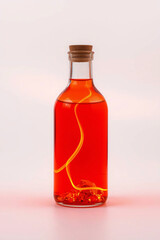 A glass bottle with red liquid and chili pepper, corked, vibrant, and transparent, showcasing a homemade chili-infused sauce.