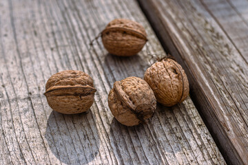 Closeup of four whole walnuts on aged wooden surface with natural textures and warm tones. Organic food, natural patterns, textures, and healthy nutrition. Copy space. Selective focus
