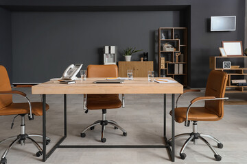 Interior of modern conference hall with table, shelving units and armchairs