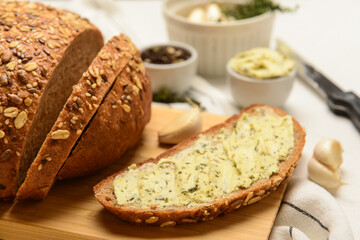 Wooden board of bread slices with fresh butter and garlic on white background