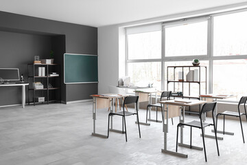 Interior of empty classroom with desks and chalkboard