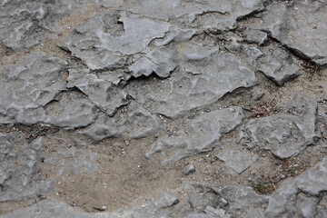 Close Up Background Texture Of Weathered Grey Sedimentary Rock (Limestone Or Sandstone) Surface With Cracks And Fragments Mixed With Sandy Soil.