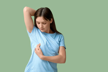 Young woman checking her breast on green background
