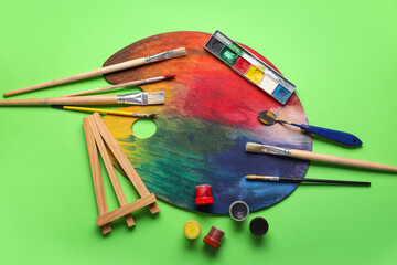 Artist brushes and palette on green background