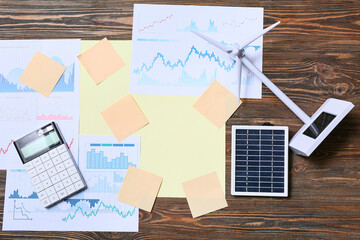Diagrams with blank sticky notes and wind turbine model on wooden background. Green Energy concept